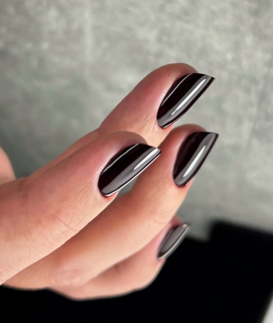 Glossy black almond nails with slim reflective edges