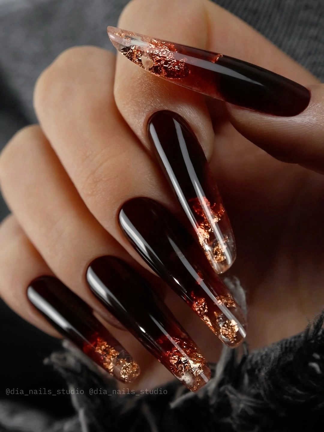 Deep burgundy almond nails with narrow copper sparkle