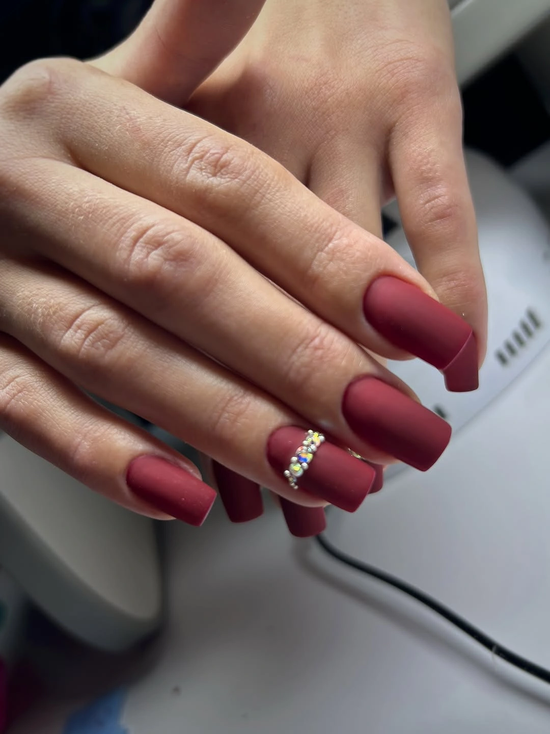 Long burgundy coffin nails with a jeweled accent nail