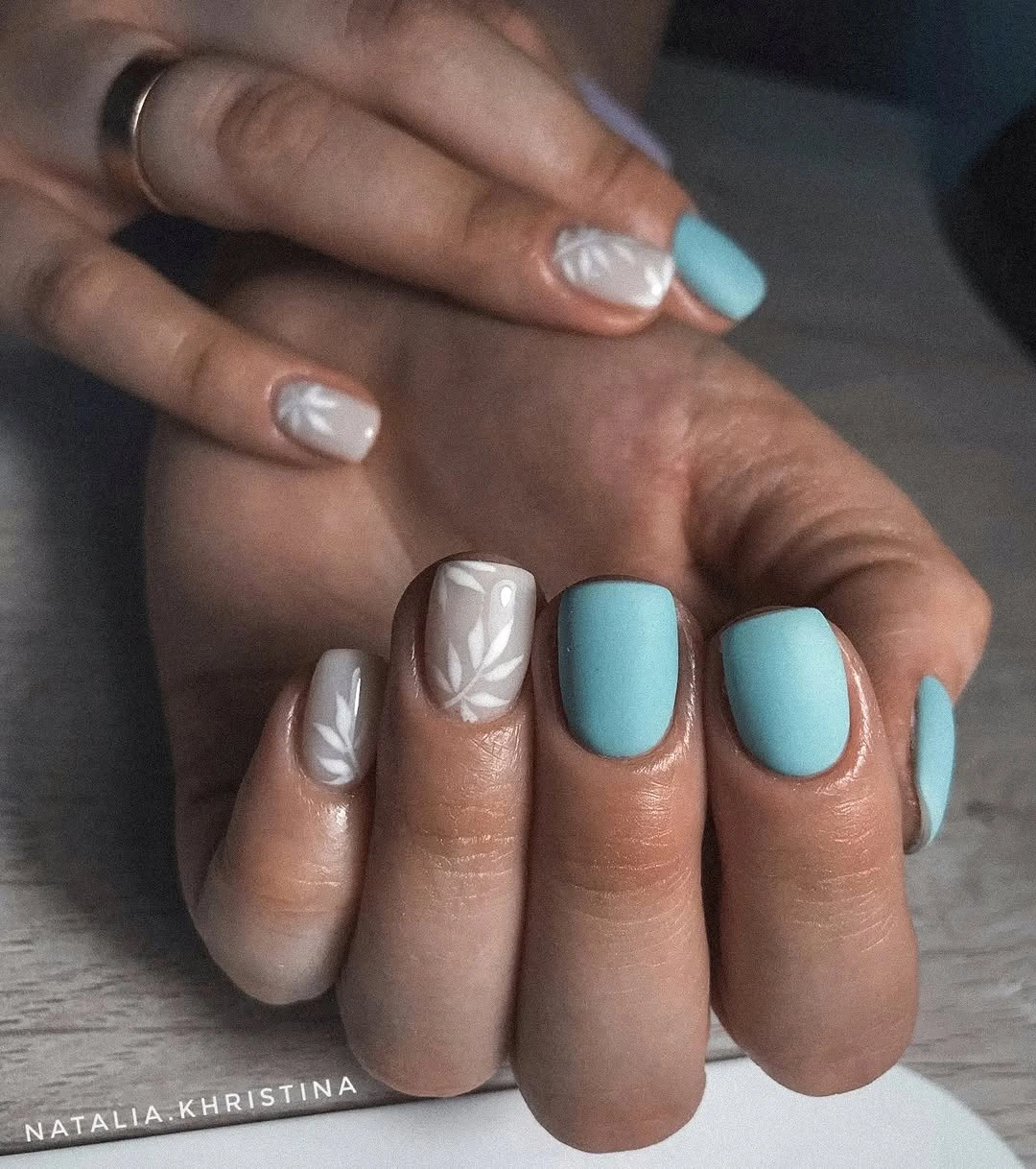 Short rounded aqua nails with pale white leaf accents