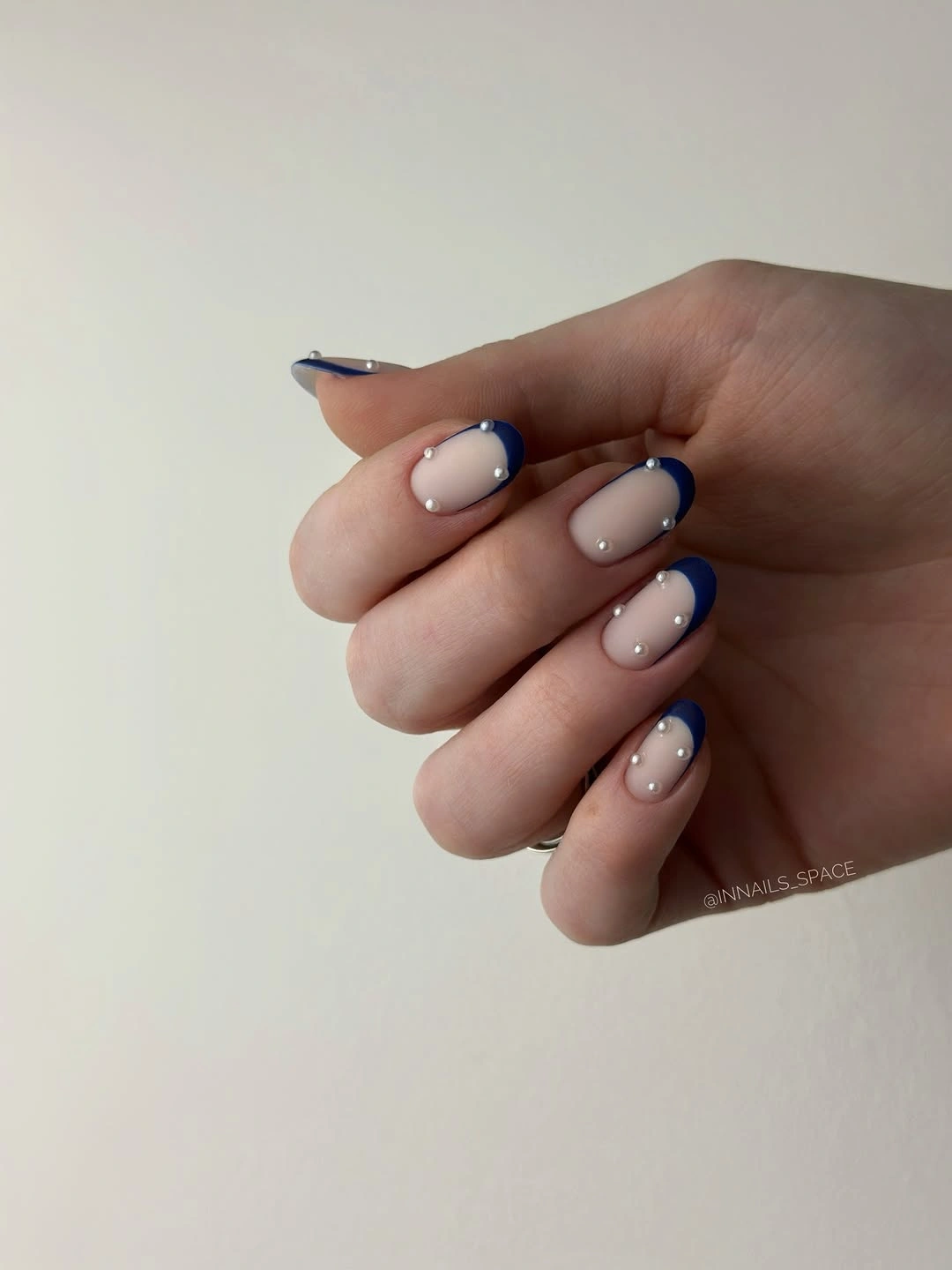 Short oval nude nails with deep navy curved tips