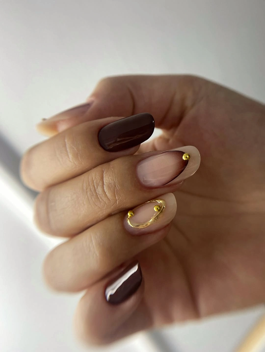 Dark chocolate oval nails with one thin gold curved accent
