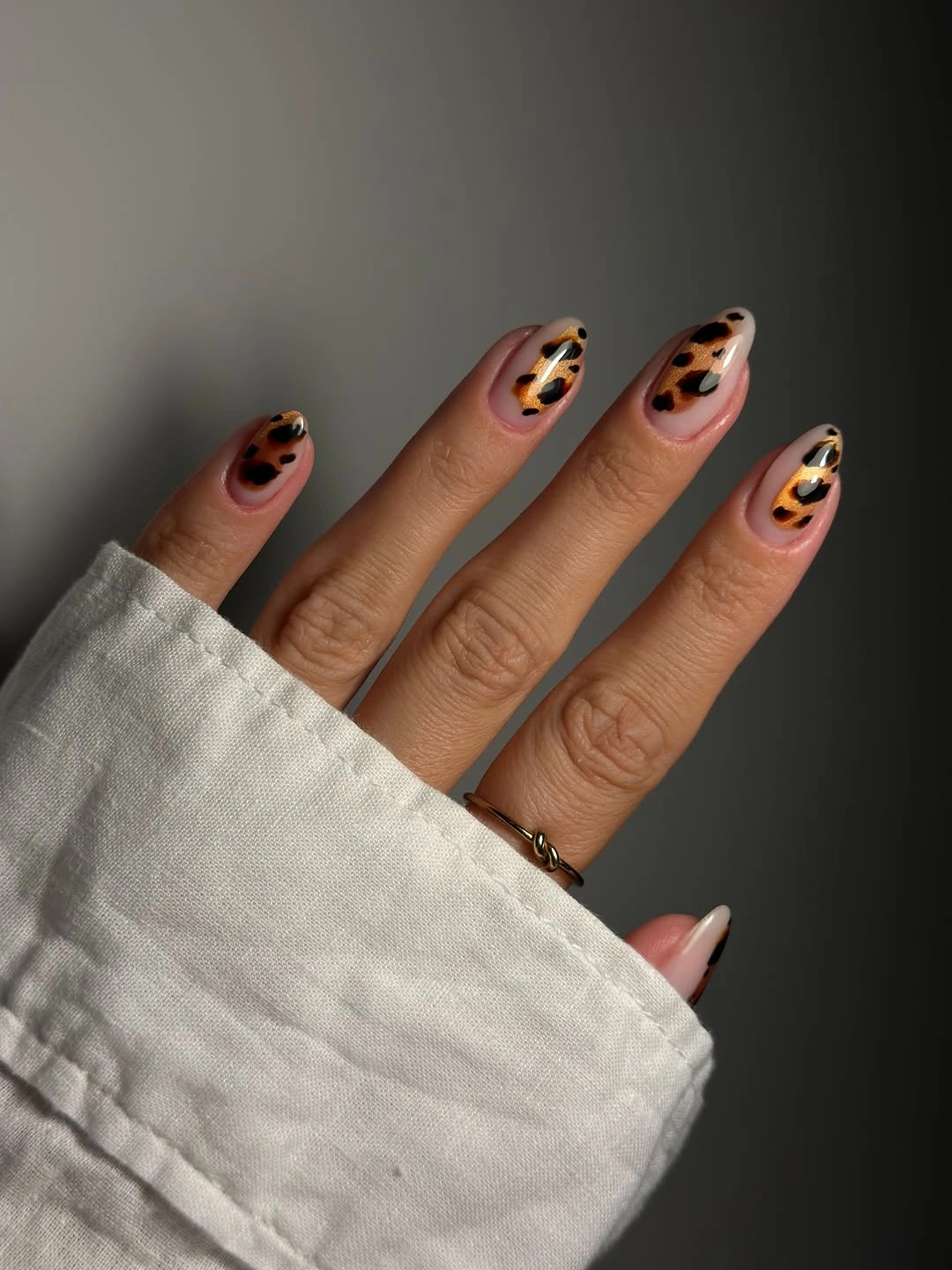 Medium almond nails with warm orange and black spotted accents