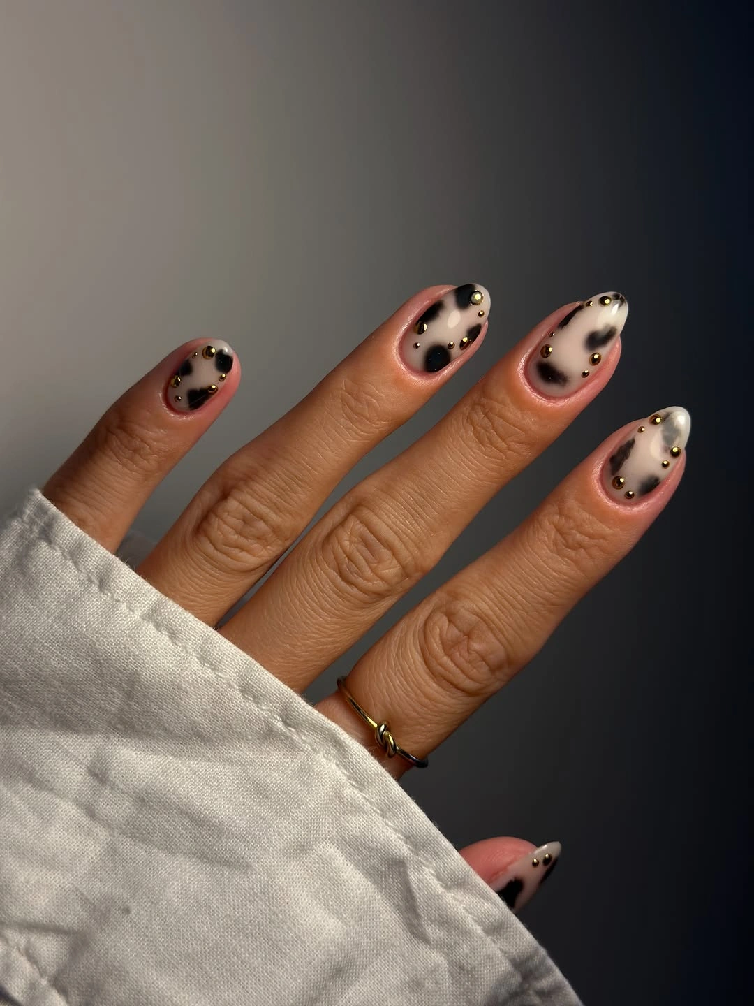 Sheer pink almond nails with brown spots and gold details