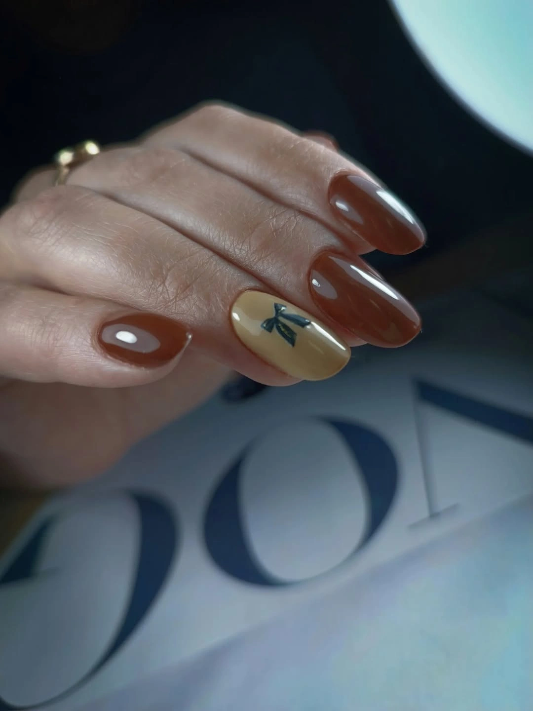 Warm brown almond nails with pale bow accent detail