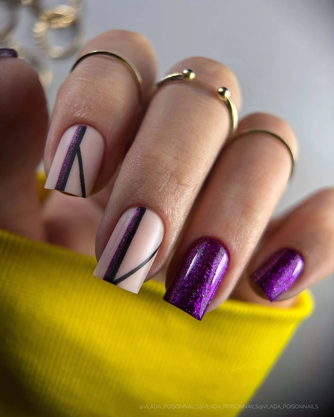 pale nails with graphic dark lines and purple glitter accents