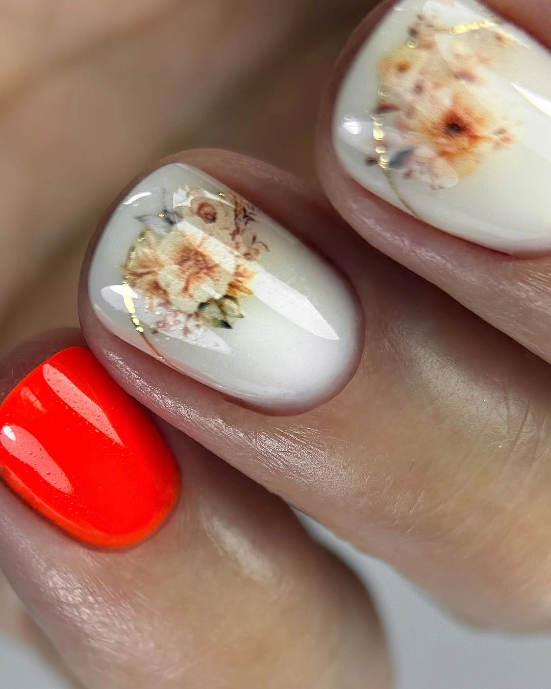 white nails with floral detail beside a vivid red accent