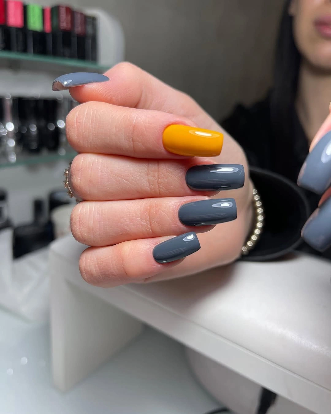 Short charcoal square nails with one bright orange accent