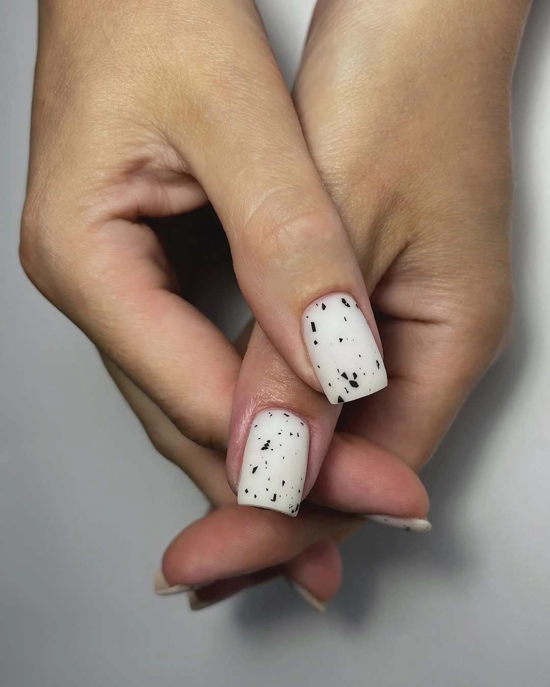 Short milky white square nails with sparse black dots
