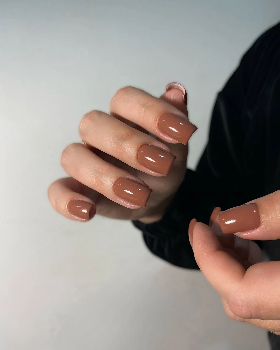 Short warm caramel glossy square nails against dark fabric