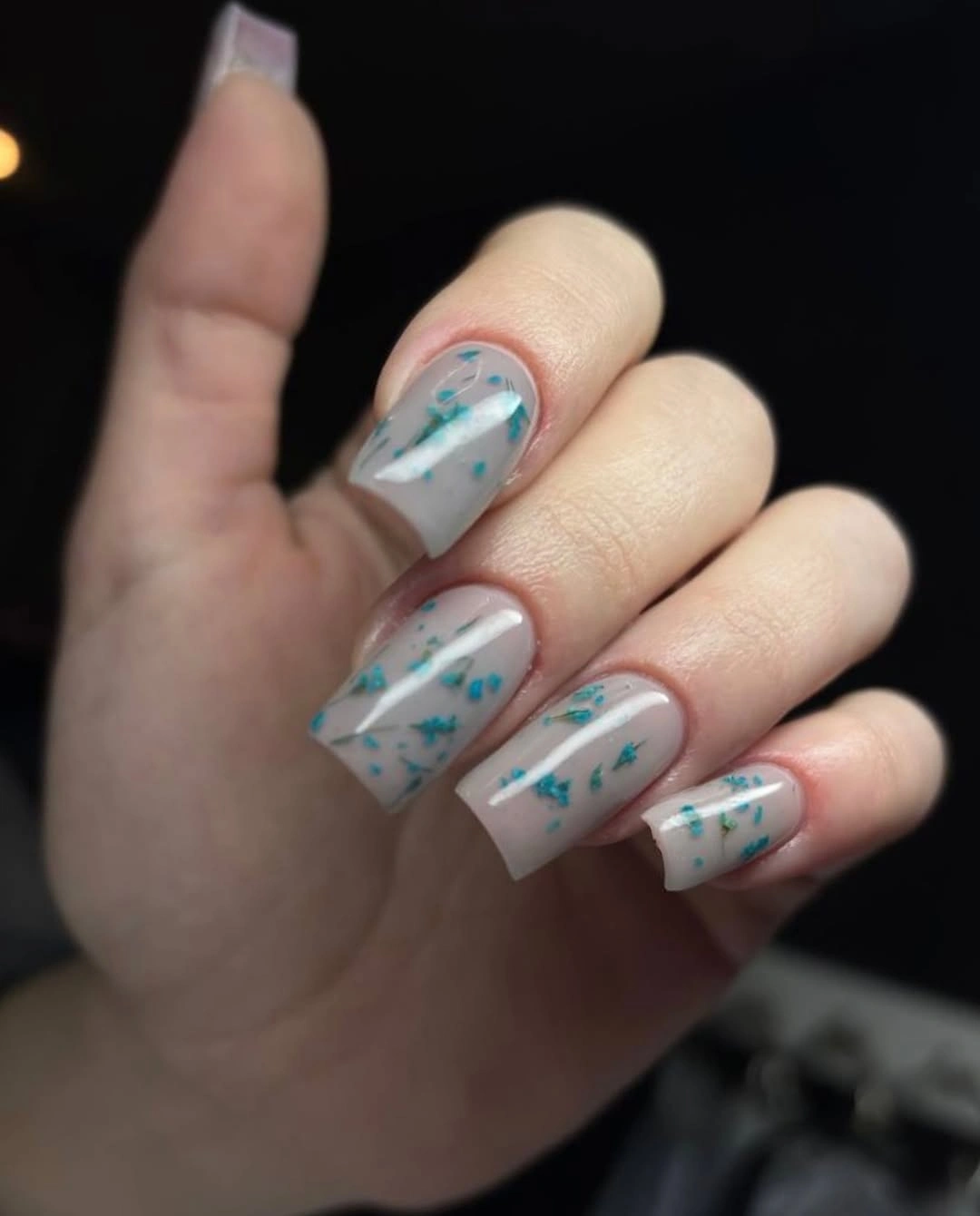 Long pale square nails with tiny turquoise accents