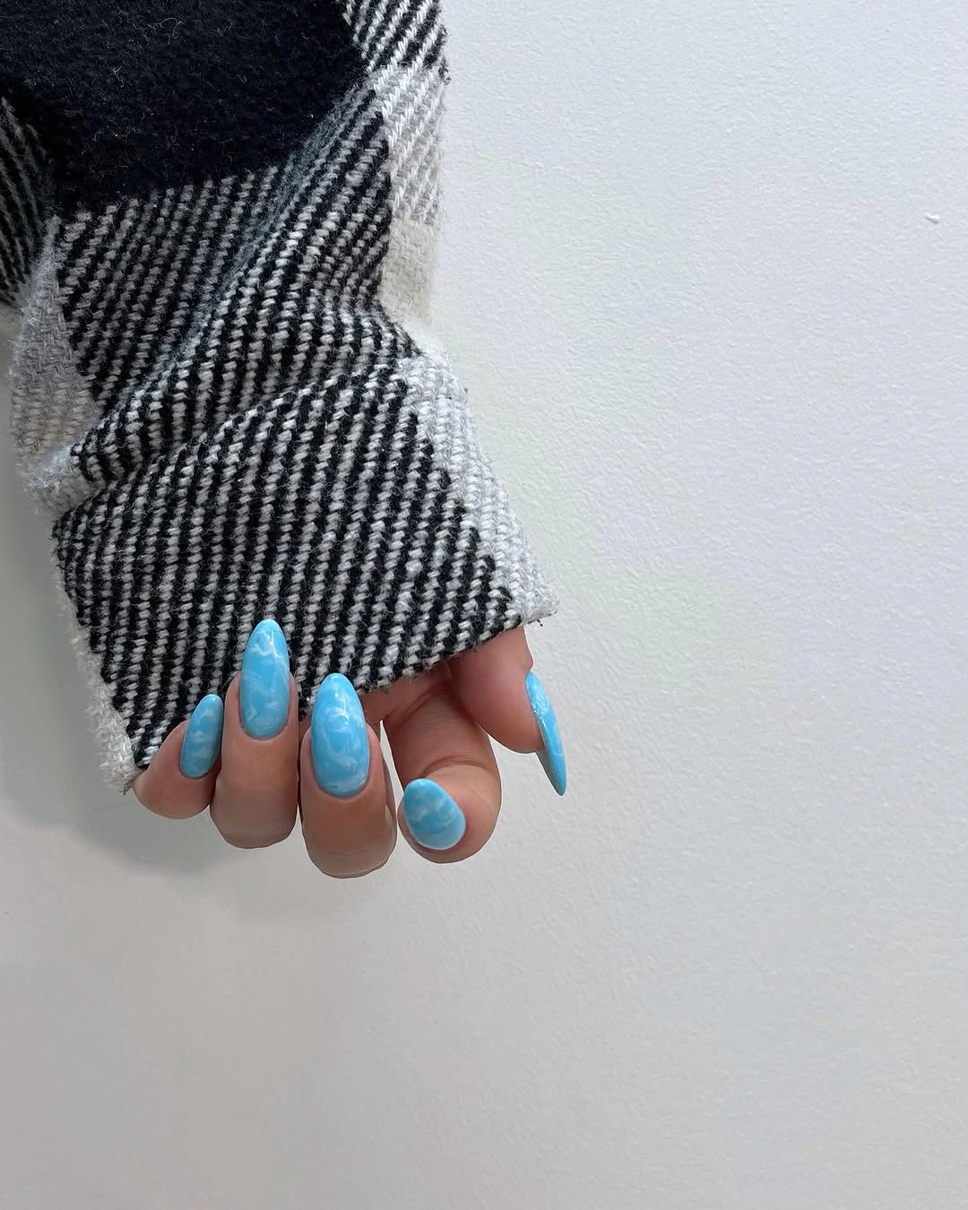 Powder blue glossy almond nails with a checked sleeve
