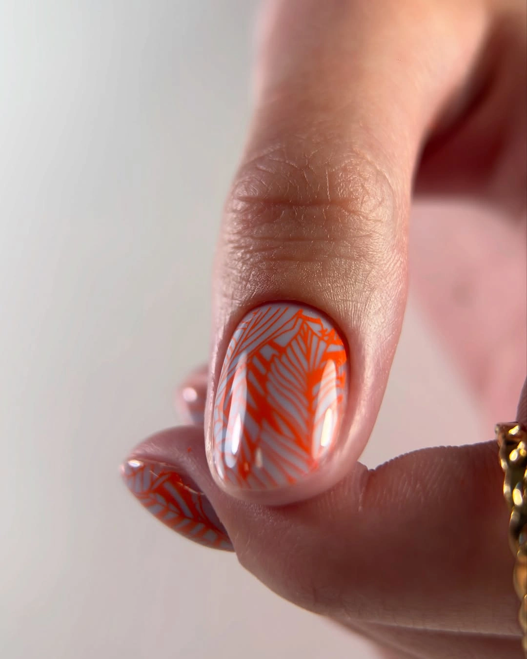 Short pale nails with orange geometric linework accent