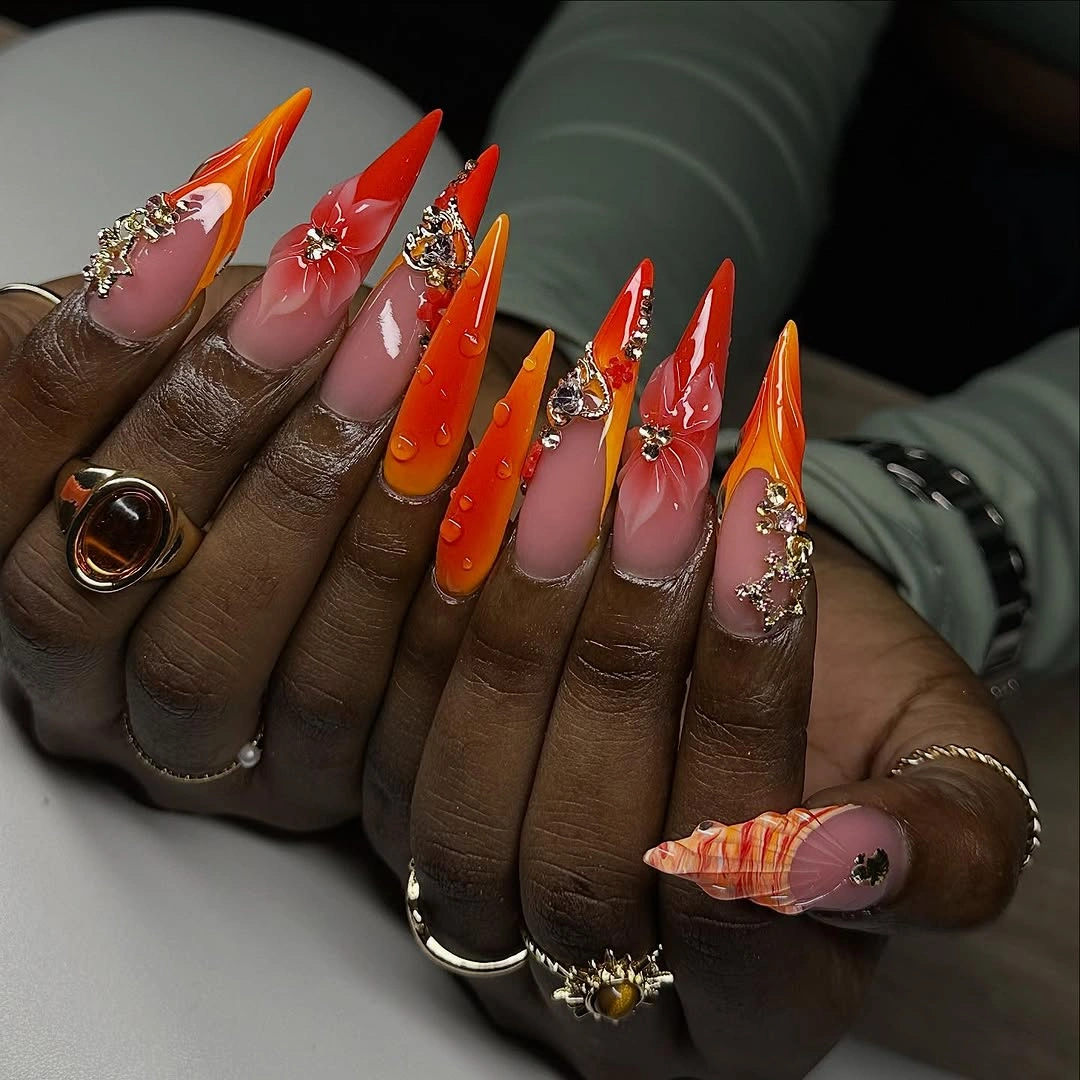 orange red stiletto nails with metallic decorative accents