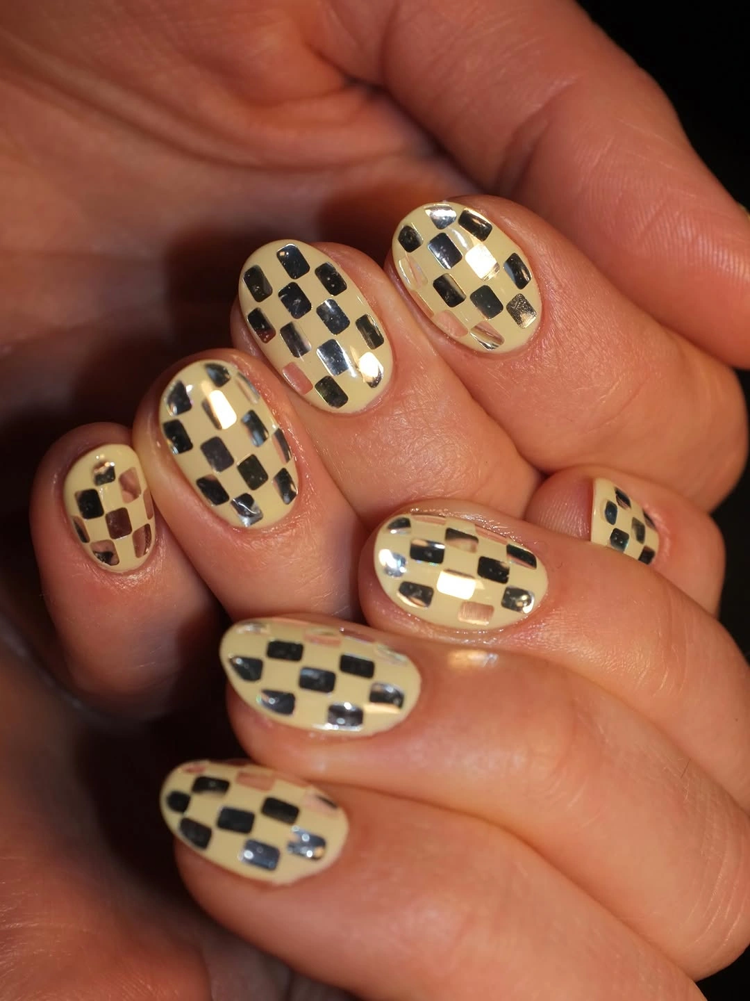 cream short nails with black checkerboard and gold details