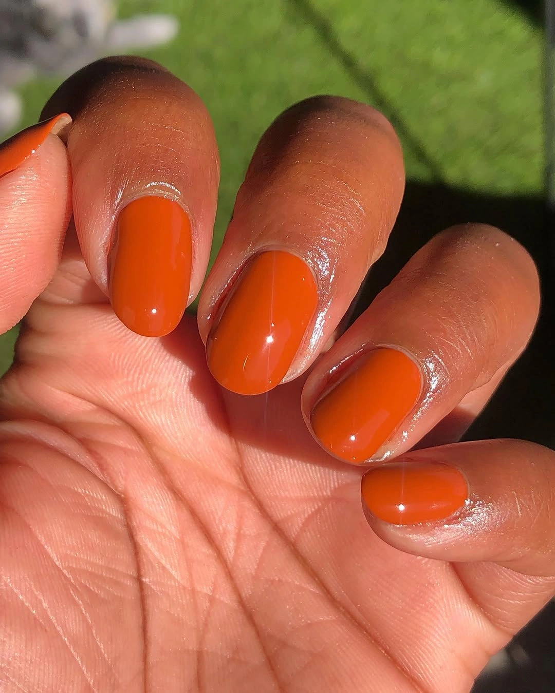 medium glossy orange oval nails in a single warm shade