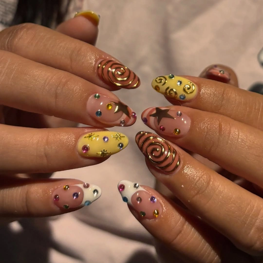 Nude pink nails with yellow swirls and tiny colorful dots