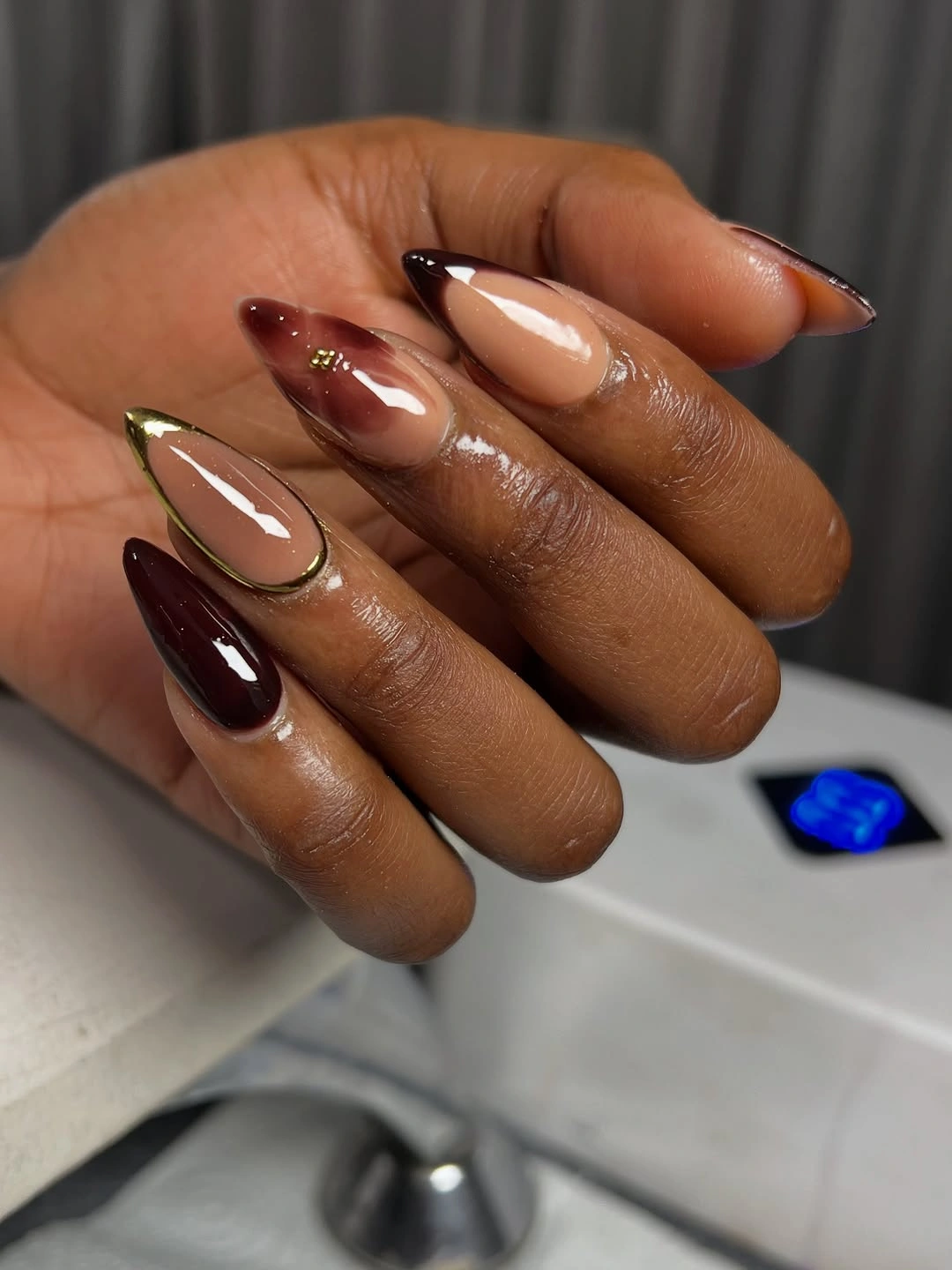 Burgundy almond nails with nude space and gold trim