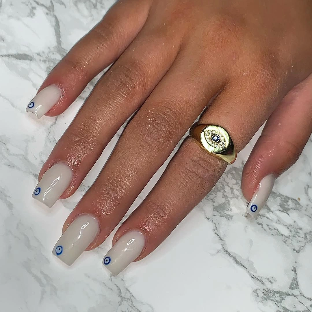 Milky white square nails with tiny blue eye motifs
