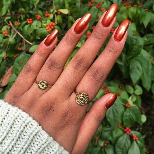 Warm copper metallic almond nails on brown skin