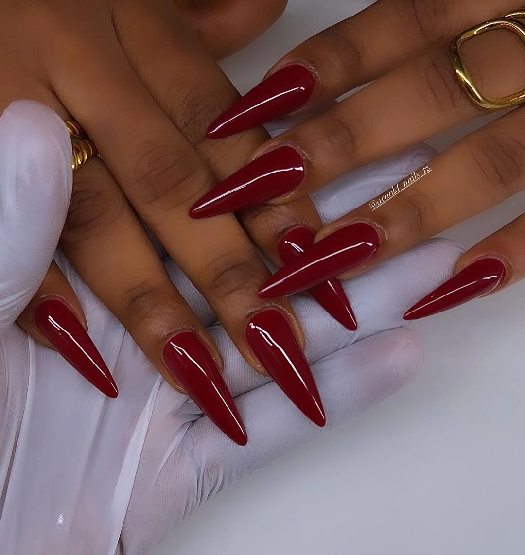 Glossy wine red stiletto nails on dark skin