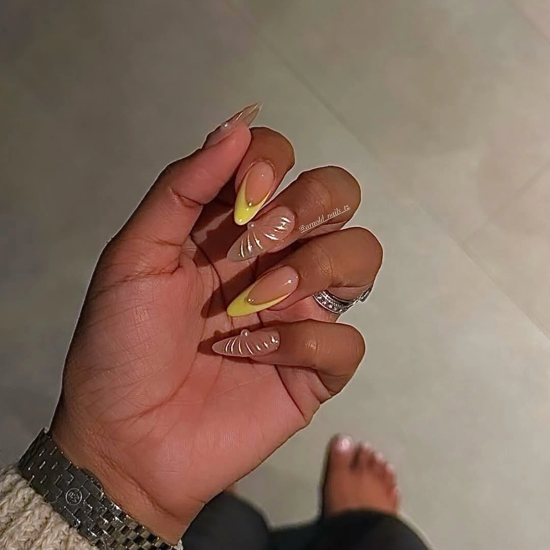 Pale yellow French nails with shell-like accents