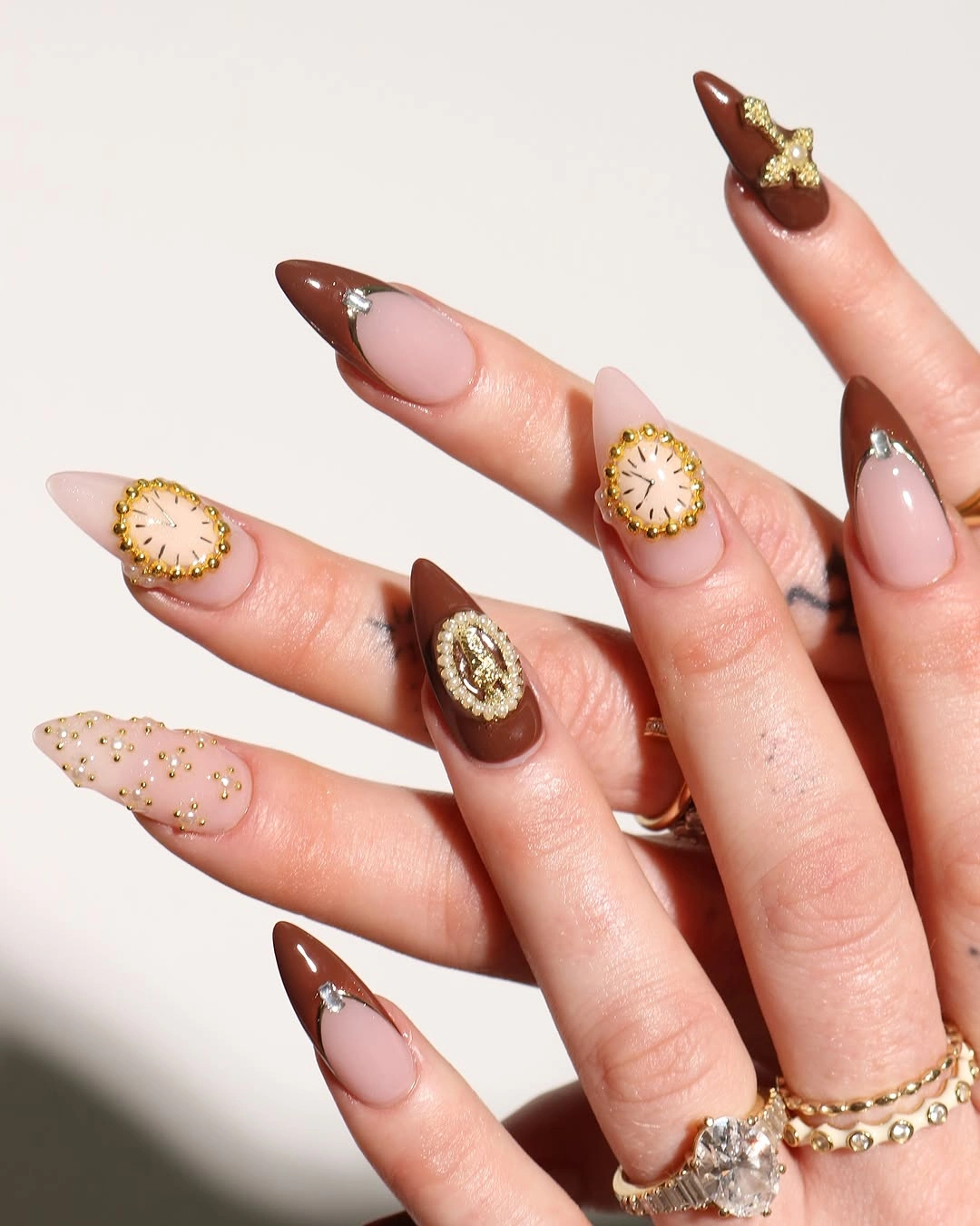 Long almond brown nude nails with round gold accents