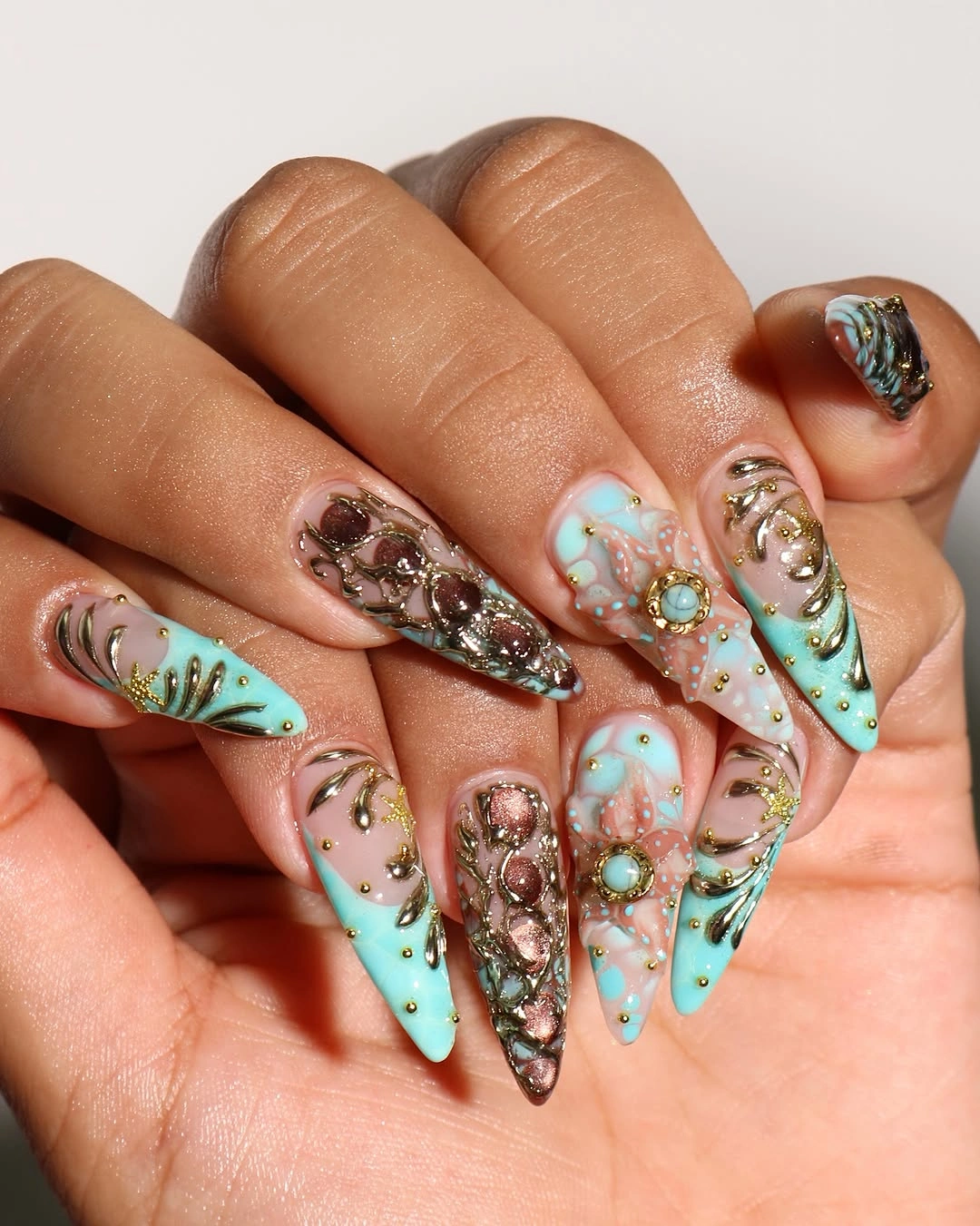 Long aqua brown and nude nails with metallic ornament