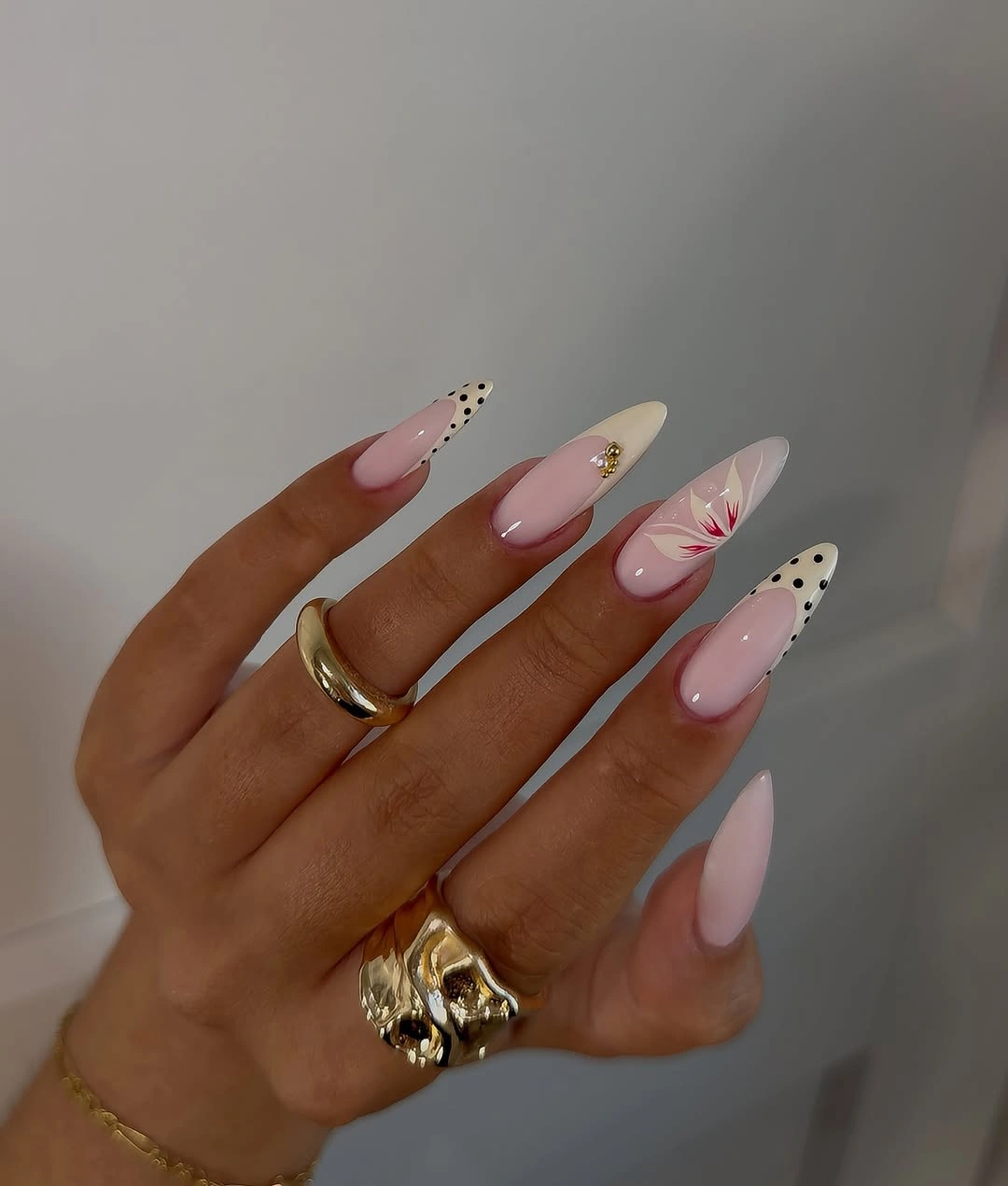 Long pink almond nails with white tips and tiny dark accents