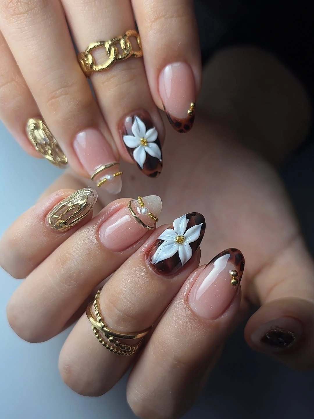 Pale pink almond nails with white flowers and gold details