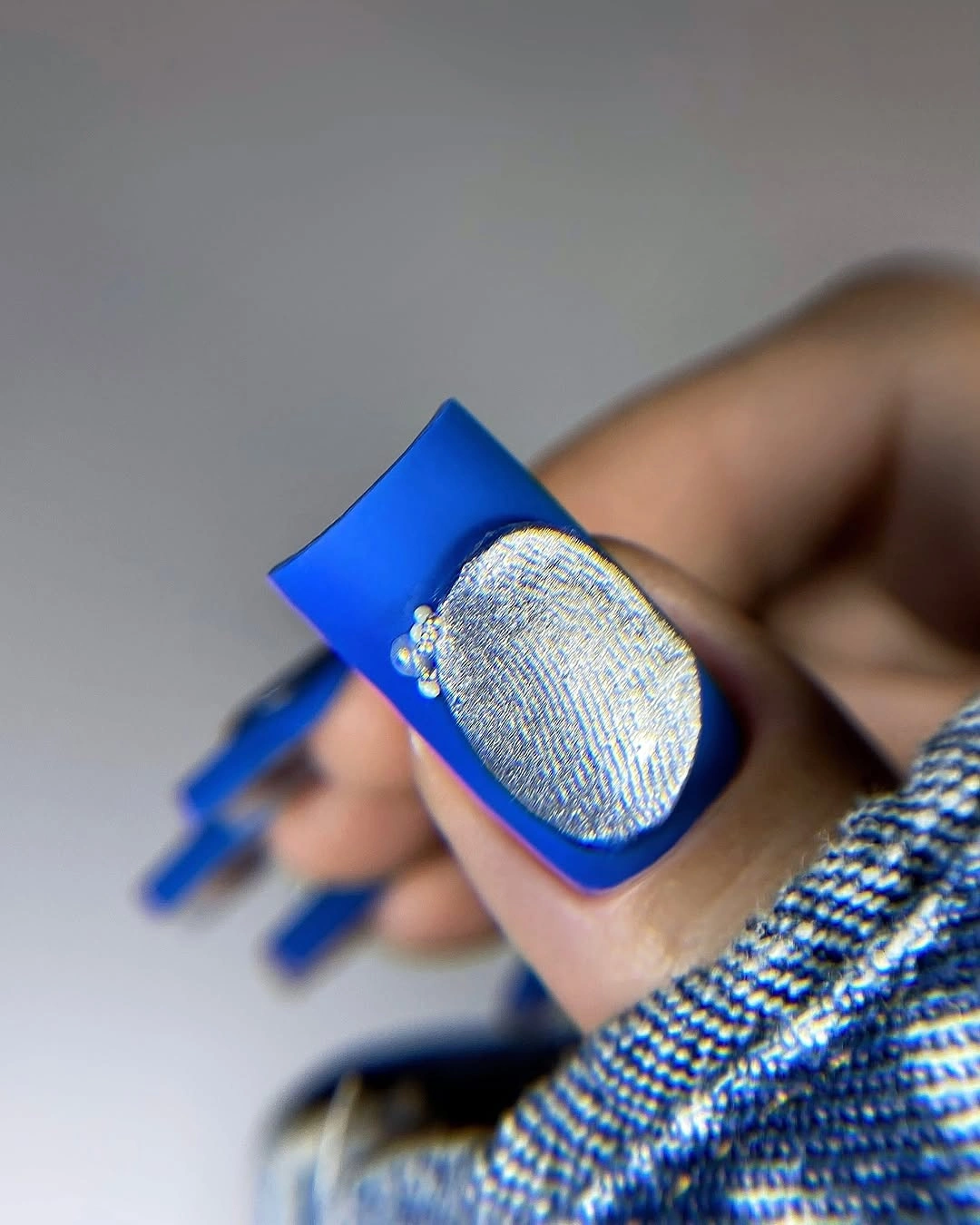 Long blue square nails with a textured silver oval accent