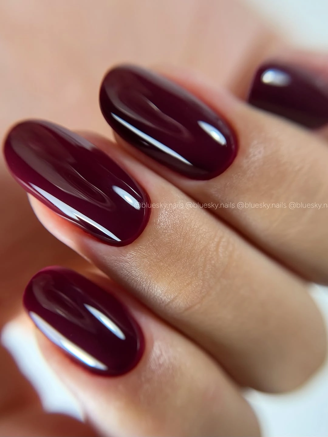 Medium almond nails in a deep glossy burgundy tone