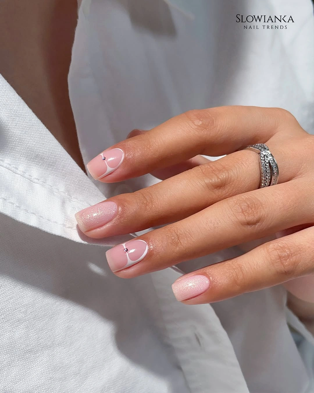 Short pale pink nails with small white curved accents