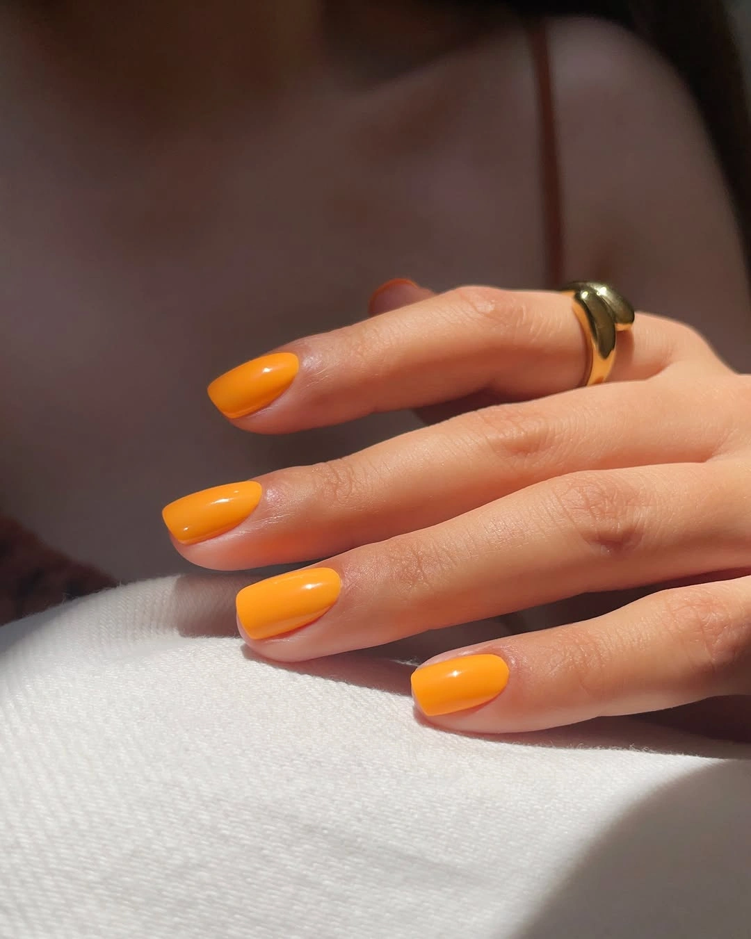 Medium almond nails painted a bright solid orange