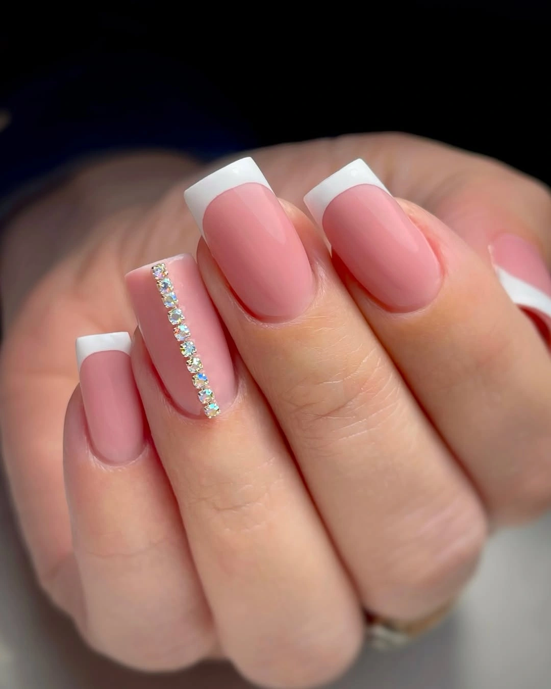 Short pink nails with white French tips and rhinestone line