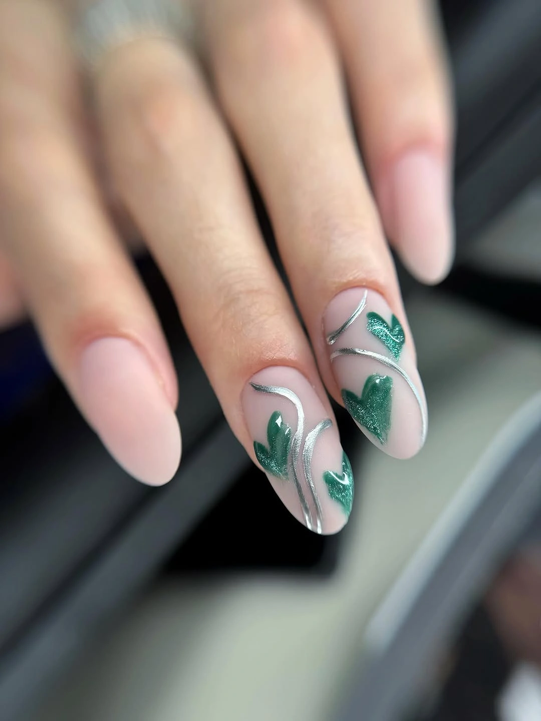 Long nude almond nails with silver curves and green hearts