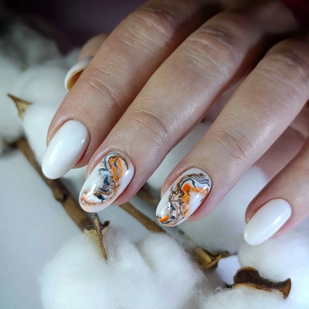 White oval nails with orange black marbled accent panels