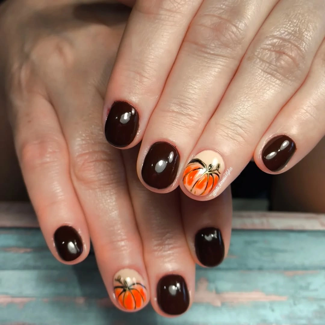 Short glossy black nails with one orange pumpkin accent