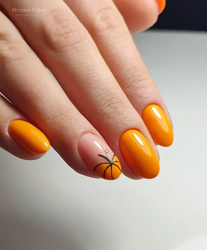 Bright orange oval nails with one black pumpkin drawing