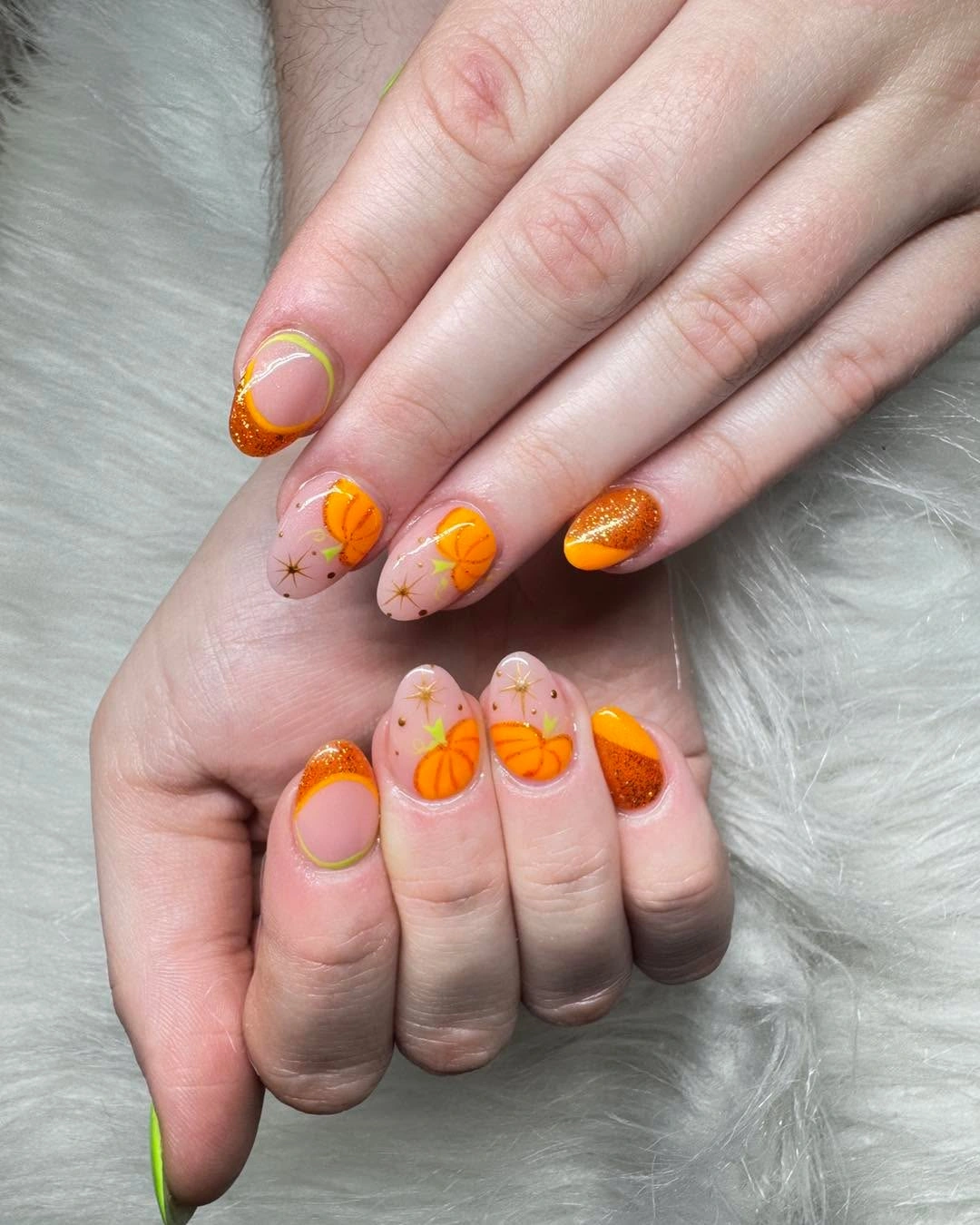 Blush oval nails with tiny pumpkins and orange tip lines