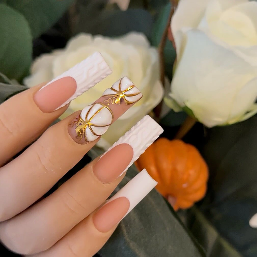 Long nude coffin nails with white tips and gold bow accents