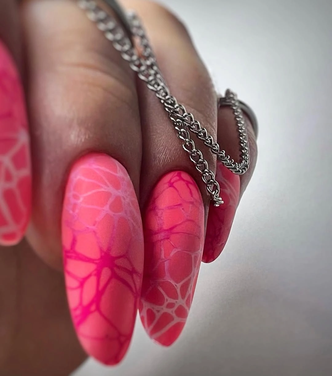 Matte neon pink almond nails with dark branching lines