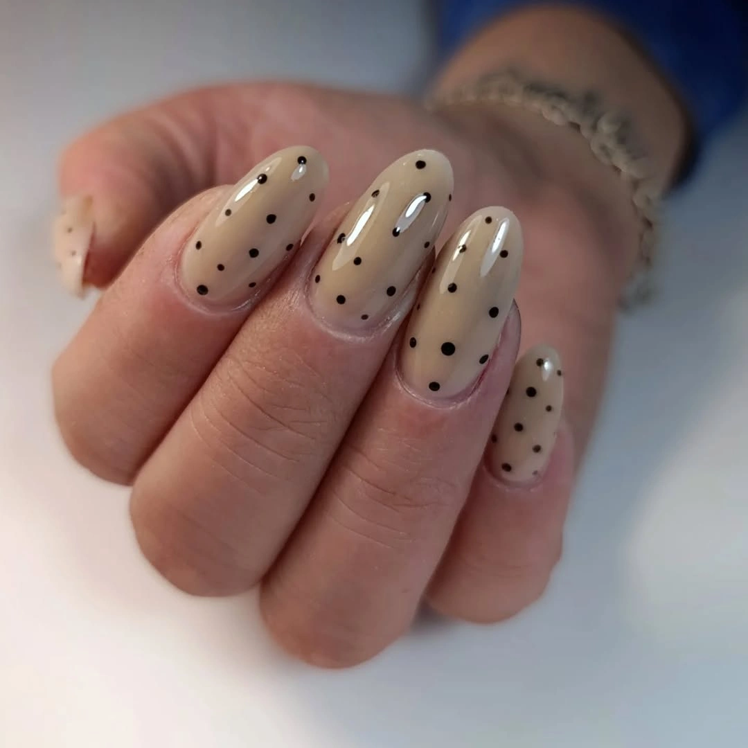 Nude almond nails with evenly spaced black dots