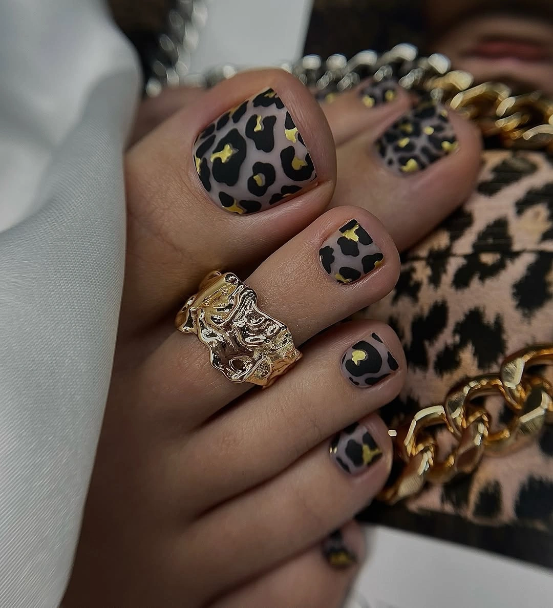 Dark square toes with tan spotted accents and metallic accessories nearby
