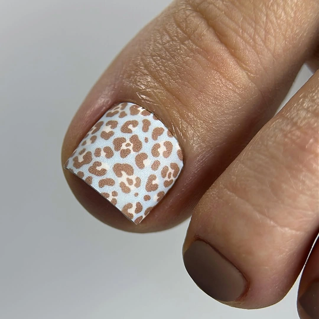 Creamy white big toe with tan leopard-like spots and plain companion toes