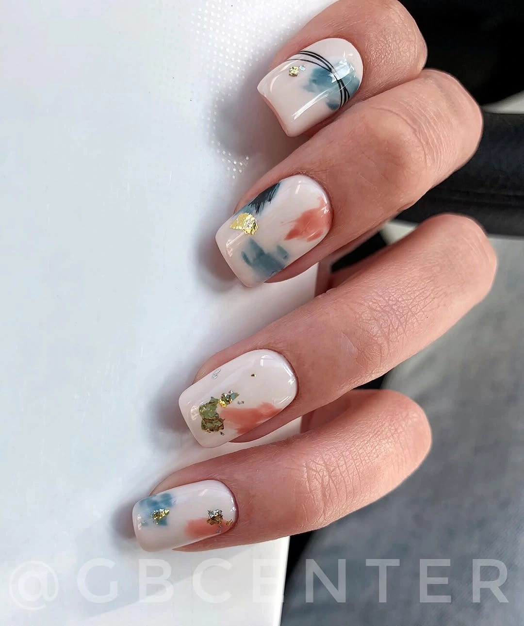 Short white square nails with small blue green yellow and orange accents