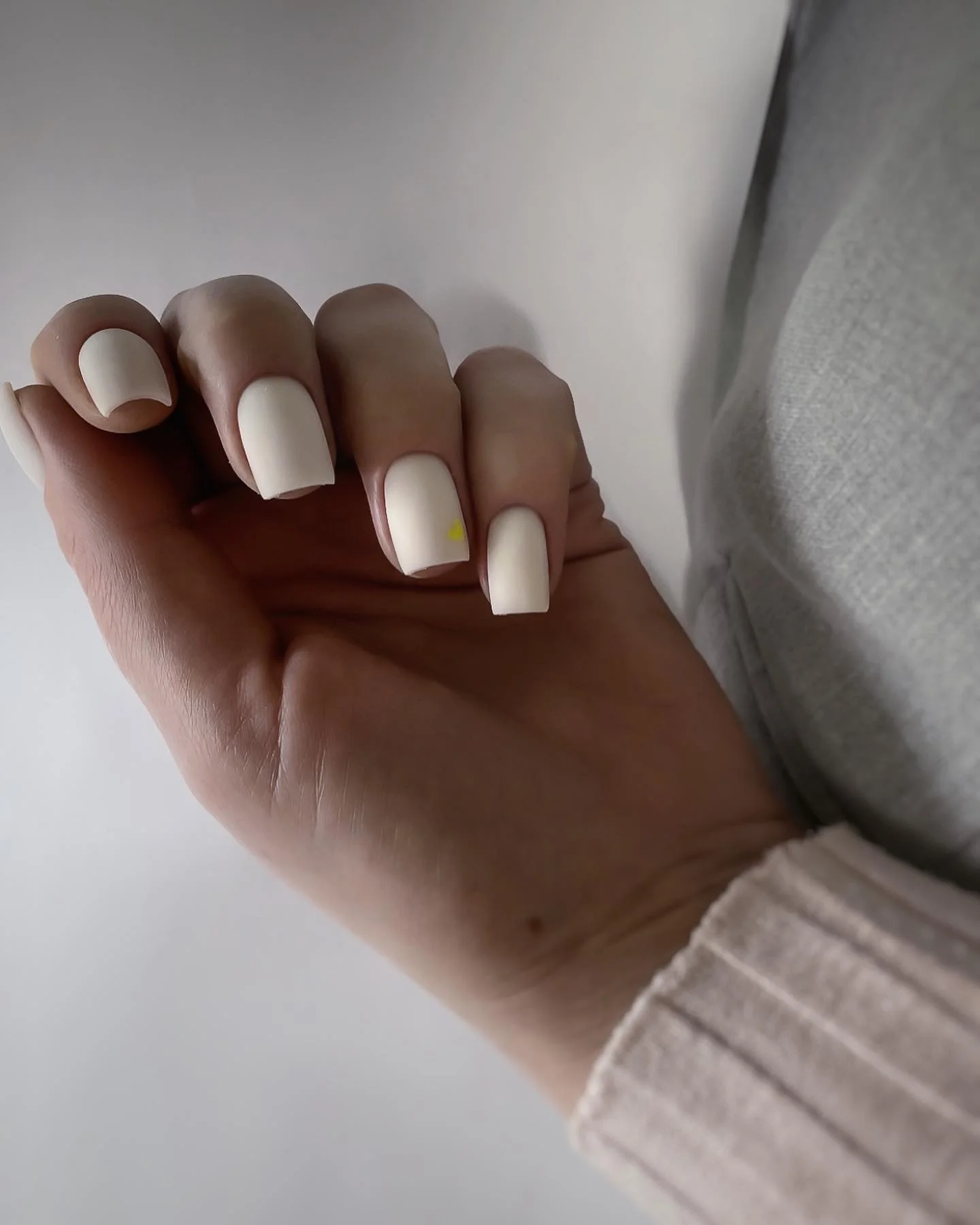 Short square milky white nails with a tiny yellow accent