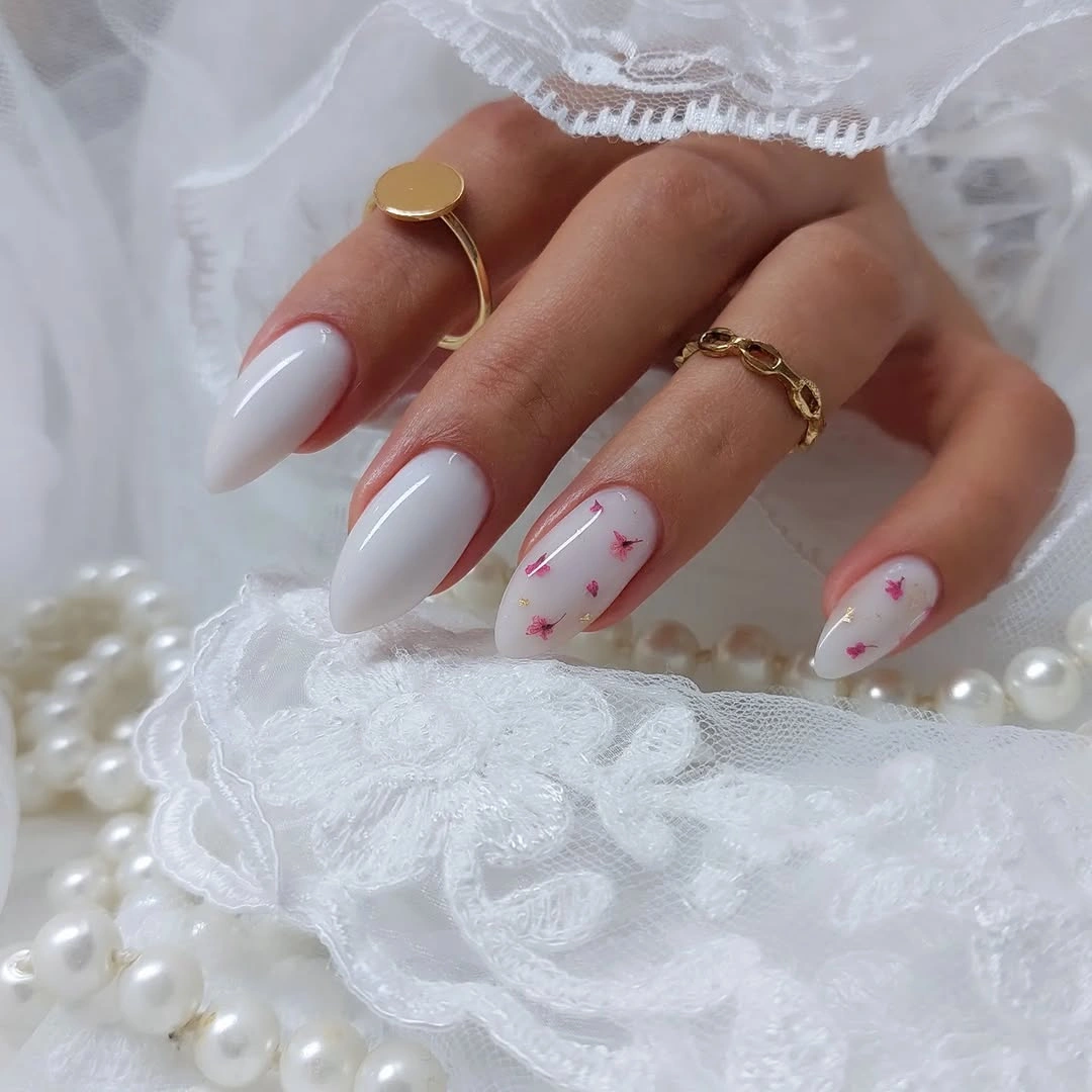 Milky white almond nails with pink floral pieces
