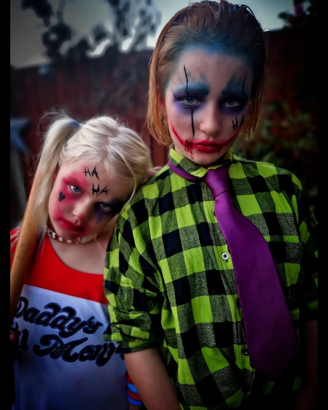 Girl in green check costume with theatrical face styling and smaller child