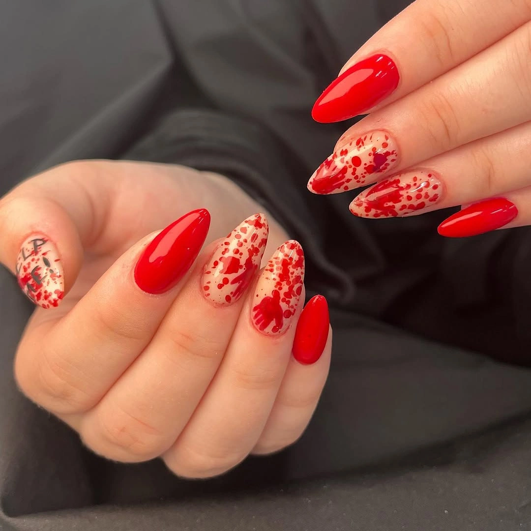 Glossy red almond nails with pale red splatter accents